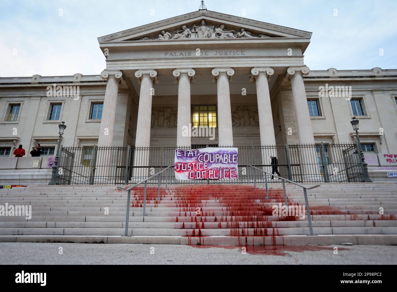 Les manifestants accrochent une bannière à la porte du palais de justice de Marseille et versent de la teinture rouge sur les marches représentant le sang des victimes du féminisme. À l'occasion de la Journée internationale des droits de la femme, plusieurs personnes ont manifesté dans les rues de Marseille. Banque D'Images