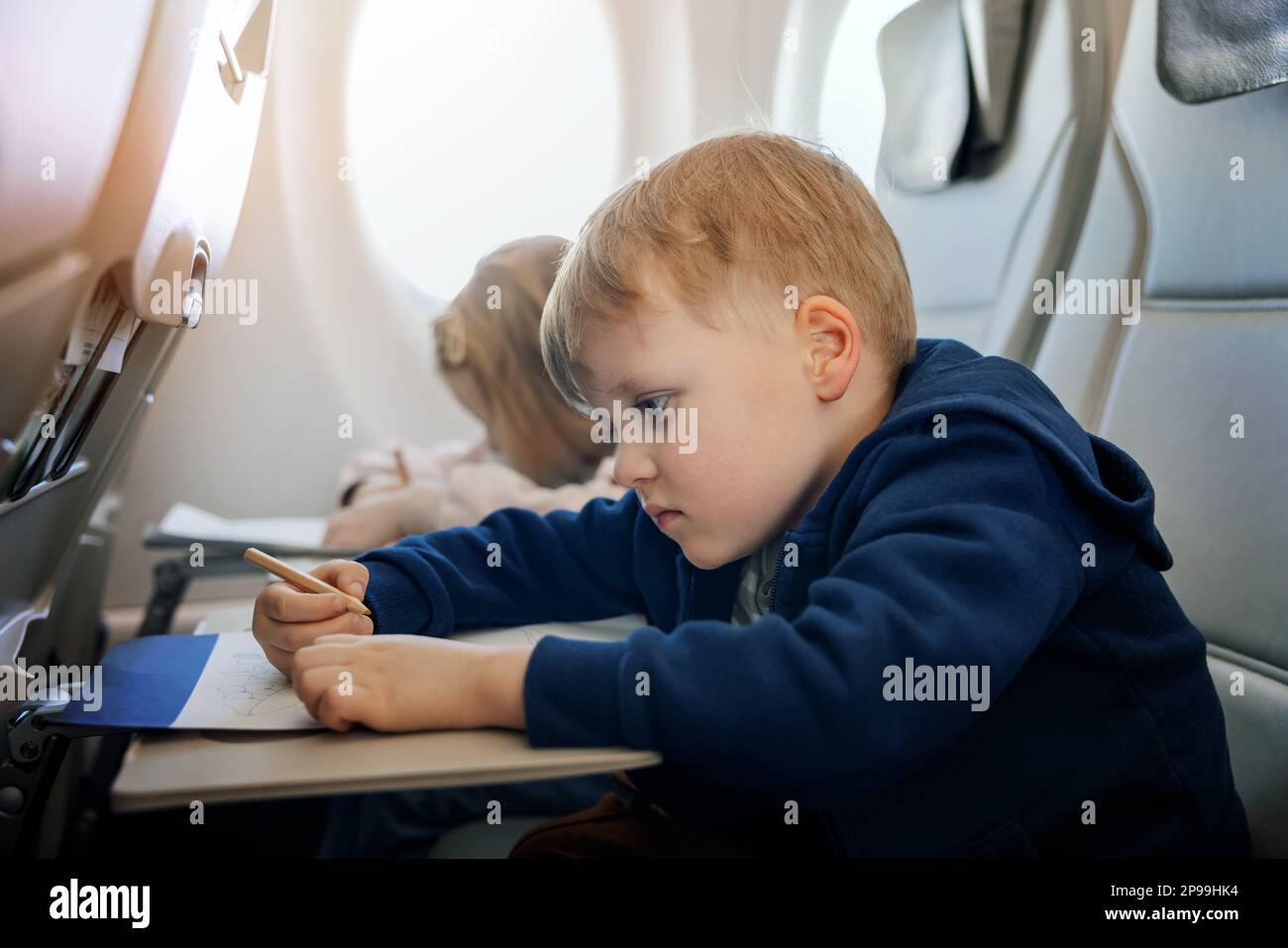 les enfants volent en avion et dessine avec un crayon dans un livre de coloriage. voyager avec des enfants Banque D'Images