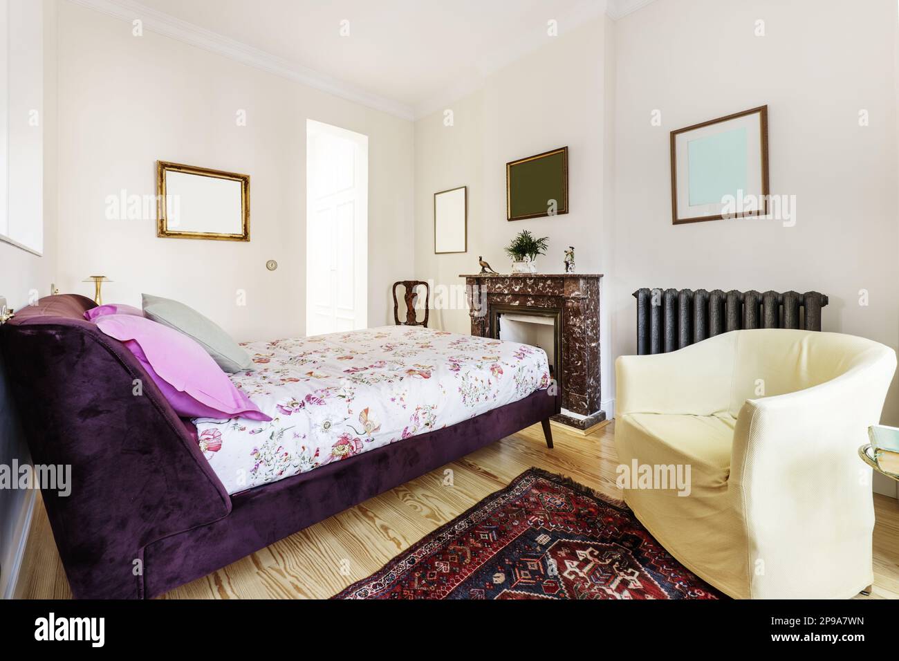 Chambre avec lits doubles, structure capitonnée en velours violet, cheminée en marbre à motif de velours brun, parquet en pin et tapis de style persan Banque D'Images