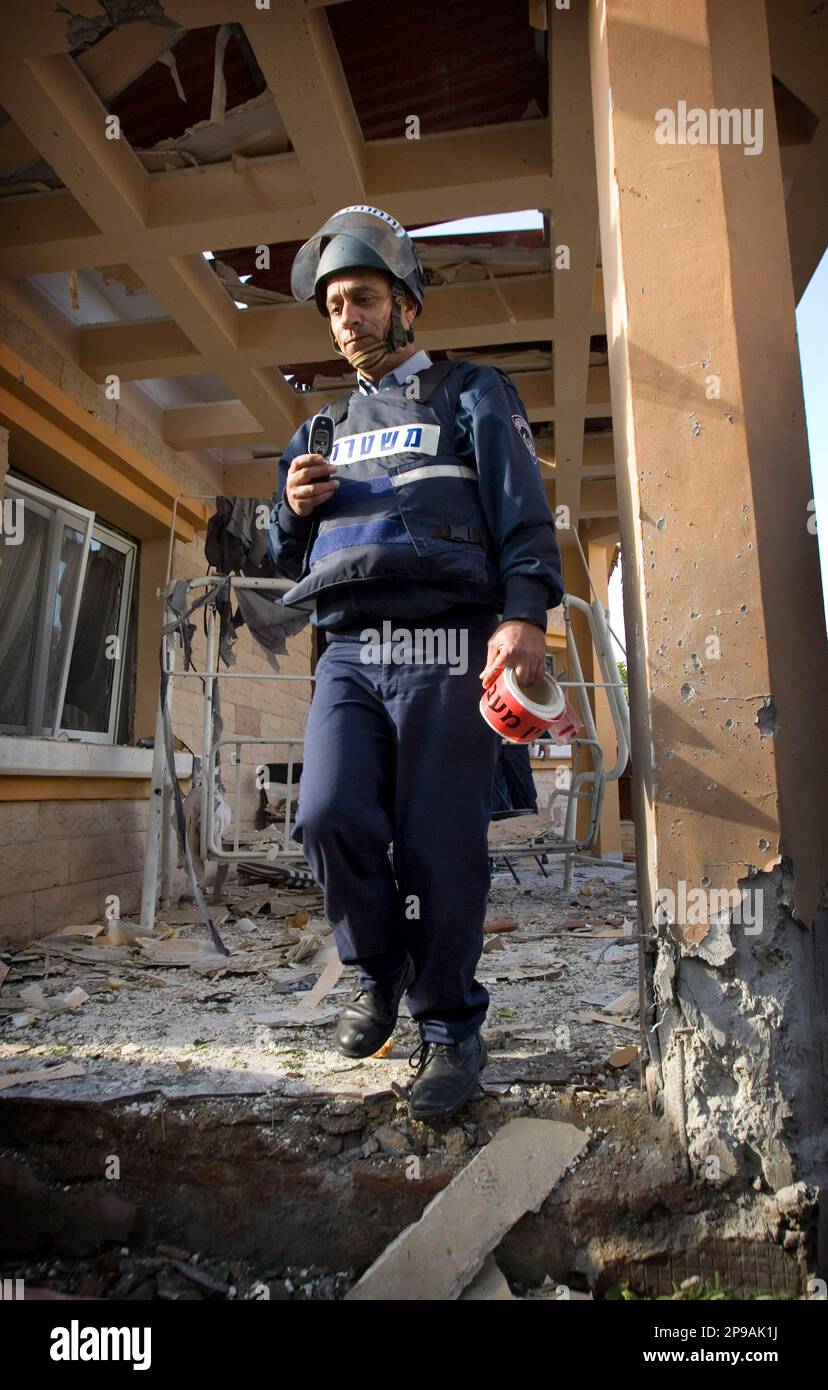 An Israeli police officer examines damage at a building after a rocket fired by Palestinian militants in Gaza hit the southern Israeli town of Sderot, Monday, Dec. 29, 2008. Israel's overwhelming air campaign against the Gaza Strip inched closer to the territory's Hamas rulers as the assault entered its third day Monday, as missiles struck a house next to the Hamas premier's home and destroyed symbols of the Islamic movement's power. (AP Photo/Ariel Schalit) Banque D'Images