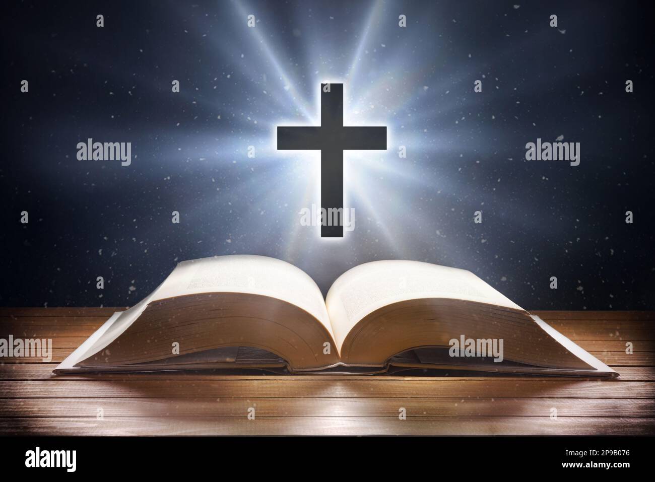 Le fond représentatif de la religion chrétienne avec la bible sur table en bois et la croix avec flash dans l'air avec le fond de l'univers. Vue avant. Banque D'Images