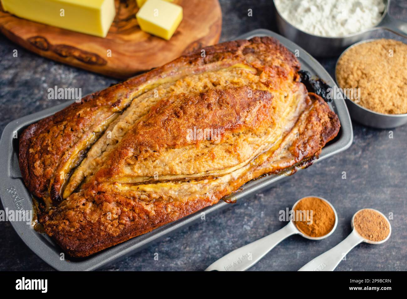Pain de banane fraîchement cuit dans un moule à pain : pain de banane dans un moule antiadhésif avec des ingrédients dans le fond Banque D'Images