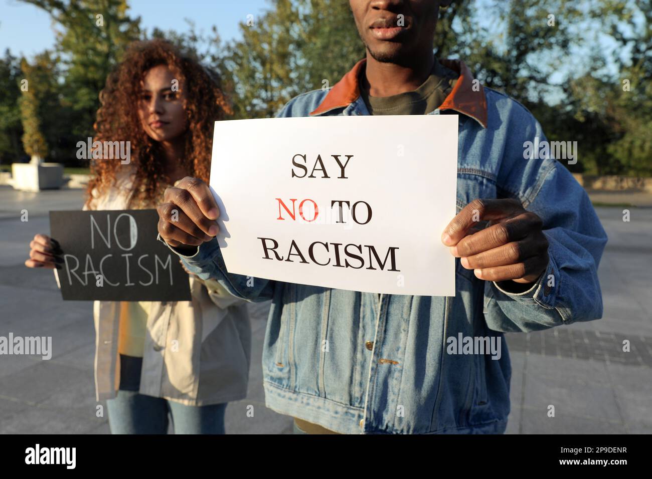 Femme et homme afro-américains tenant des signes avec des mots dire non au racisme en plein air, gros plan Banque D'Images
