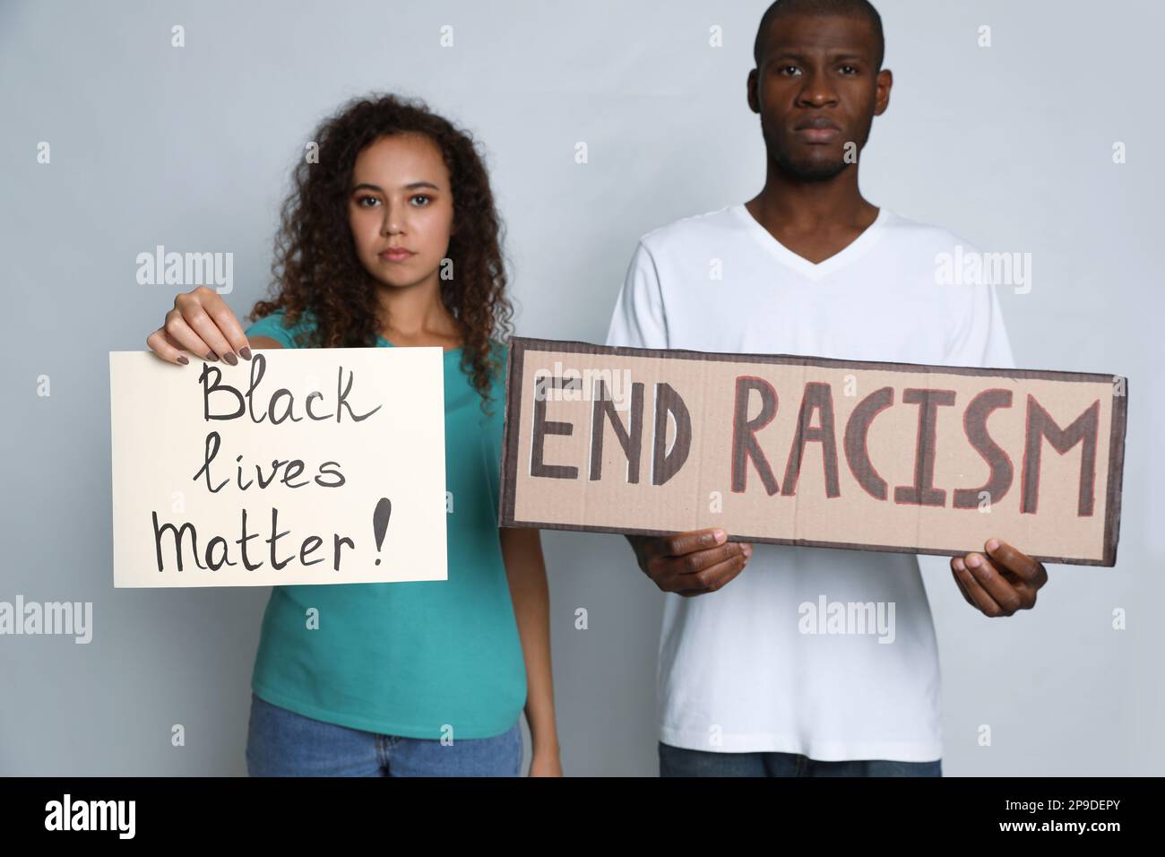 Femme et homme afro-américains portant des signes sur fond gris. Concept de racisme Banque D'Images