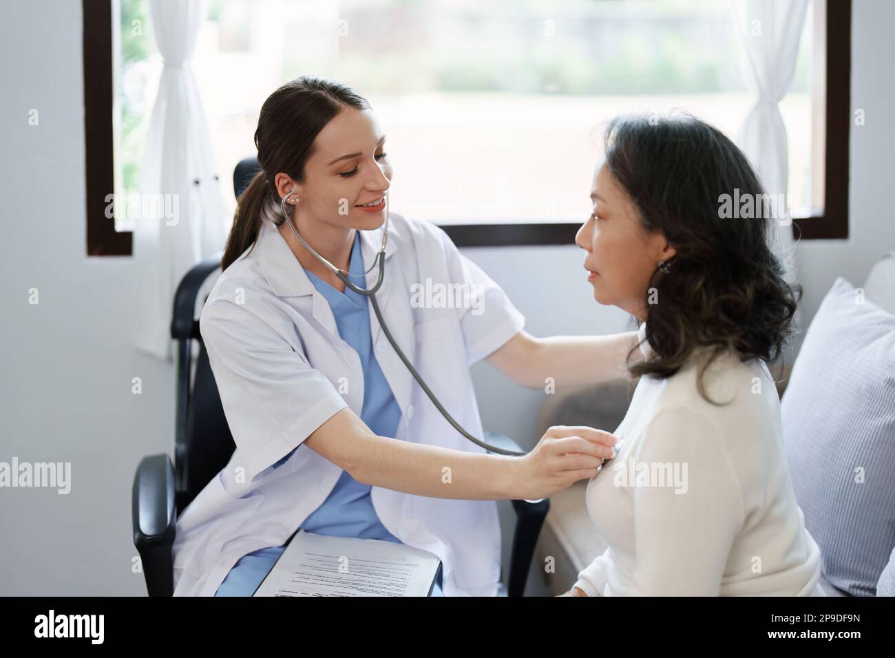 Portrait d'une femme médecin utilisant un stéthoscope pour vérifier le pouls d'un patient âgé. Banque D'Images