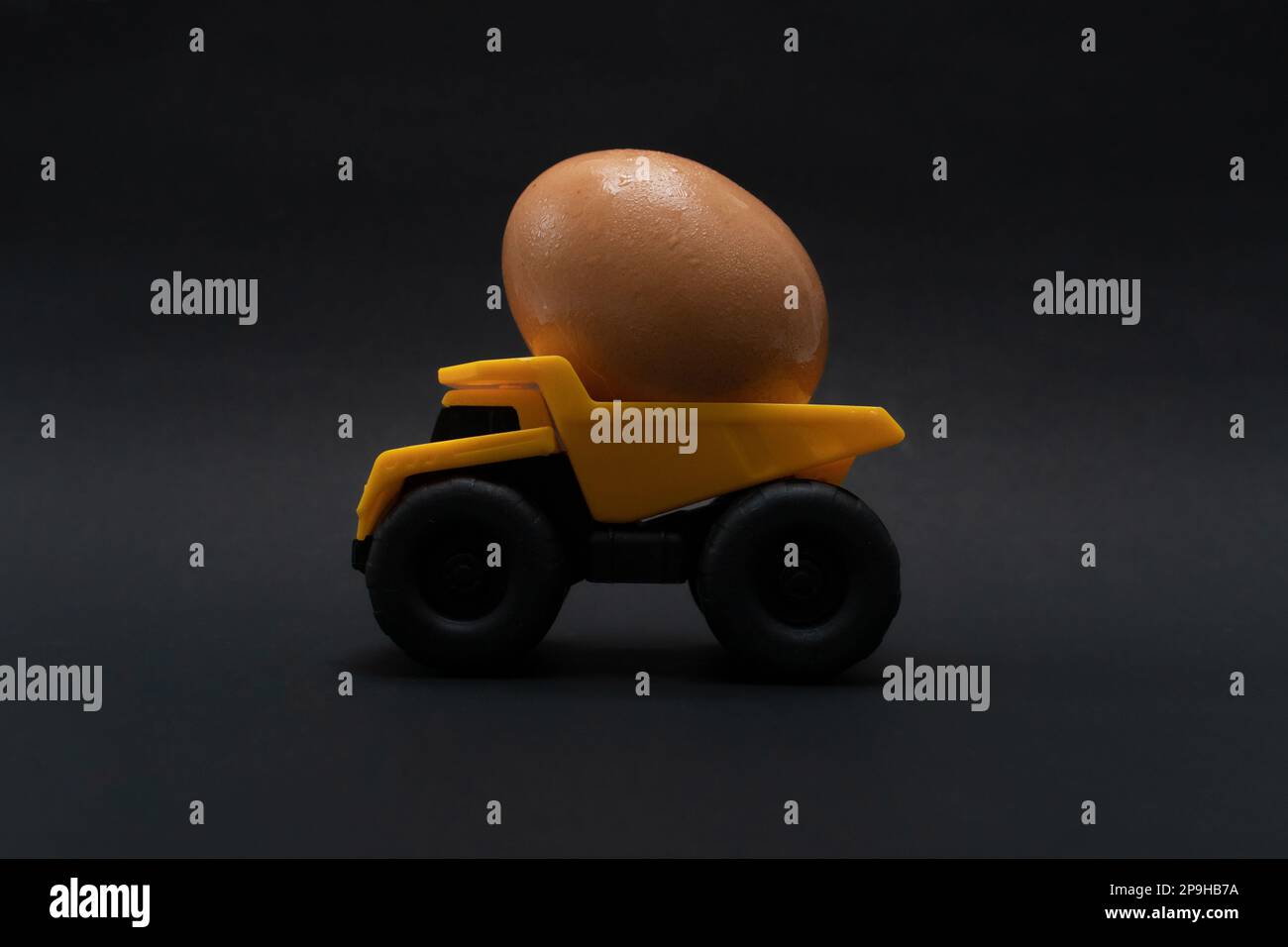 Une photo après quelques modifications, un camion jaune tente de porter un œuf. Banque D'Images