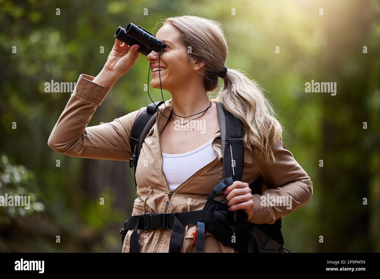 Jumelles, femme forêt et randonnée pour voyage, aventure dans la jungle et exploration de la nature avec sac à dos et équipement. Randonneur ou campeur heureux Banque D'Images