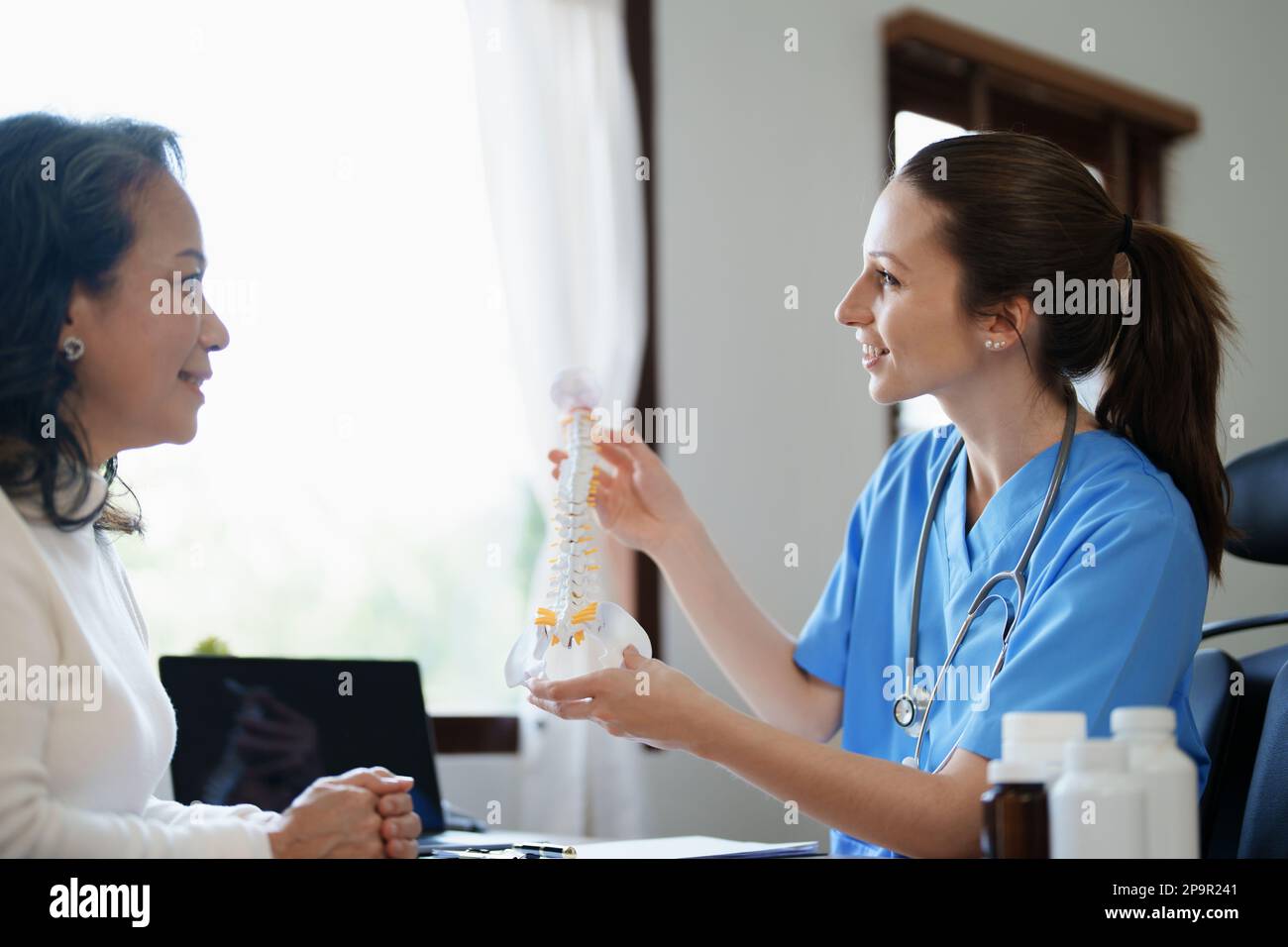 Portrait d'une femme médecin parlant à un patient âgé de la détérioration herniée du disque à partir de longues heures de travail. Banque D'Images