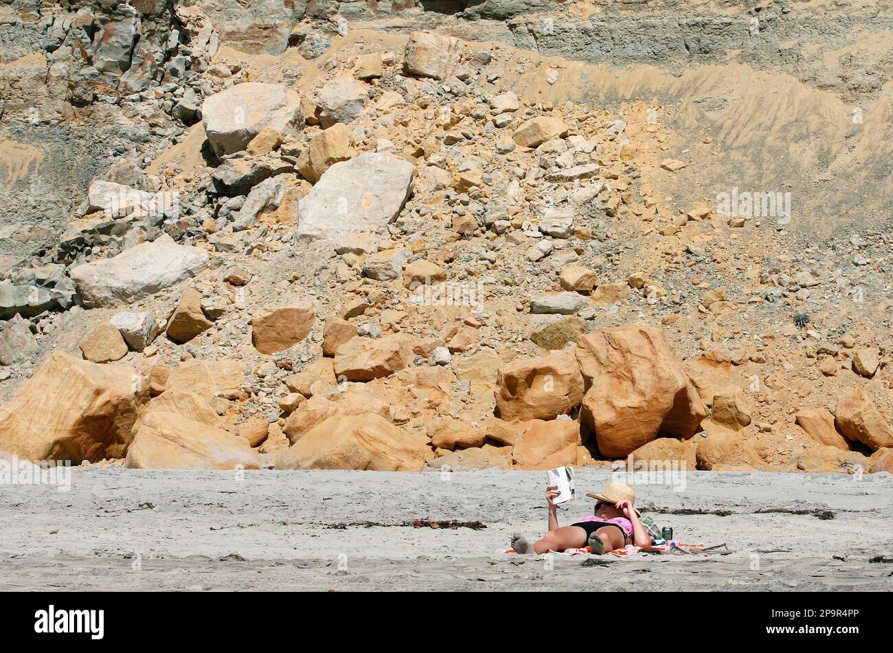 A woman reads on the beach close to a stretch of oceanside bluff below the Torrey Pines Golf Course after it collapsed and killed a man, authorities said, in San Diego Wednesday, Aug. 20, 2008. (AP Photo/Denis Poroy) Banque D'Images