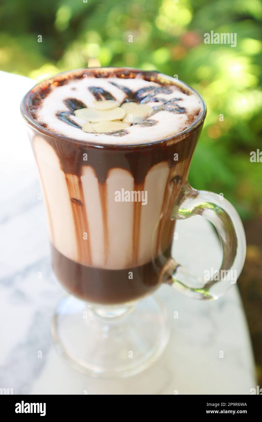 Délicieux chocolat chaud dans un verre garni d'amandes en tranches Banque D'Images