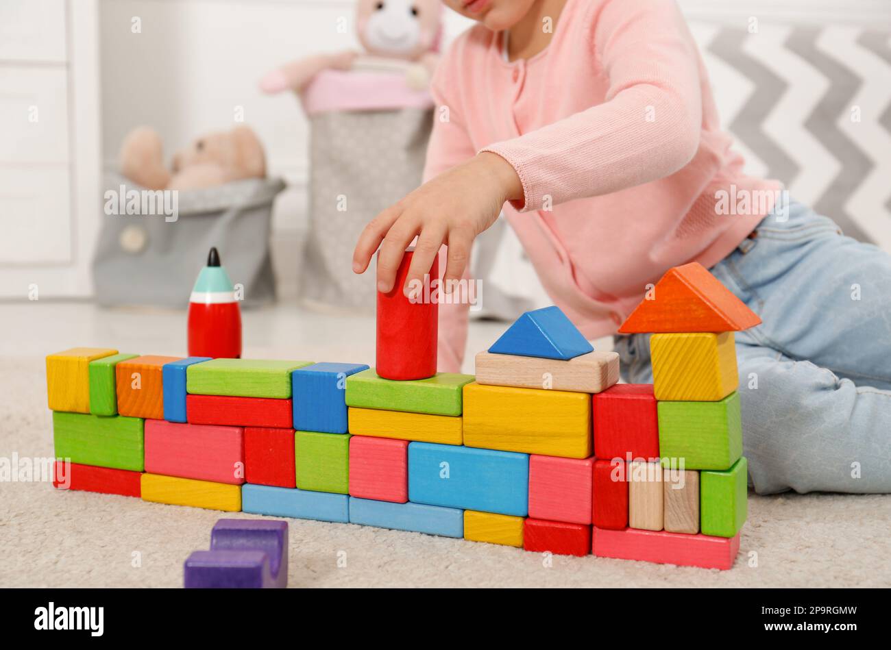 Jolie petite fille jouant avec des blocs de construction colorés à la maison, gros plan Banque D'Images