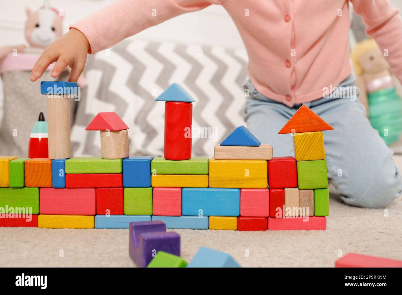 Jolie petite fille jouant avec des blocs de construction colorés à la maison, gros plan Banque D'Images