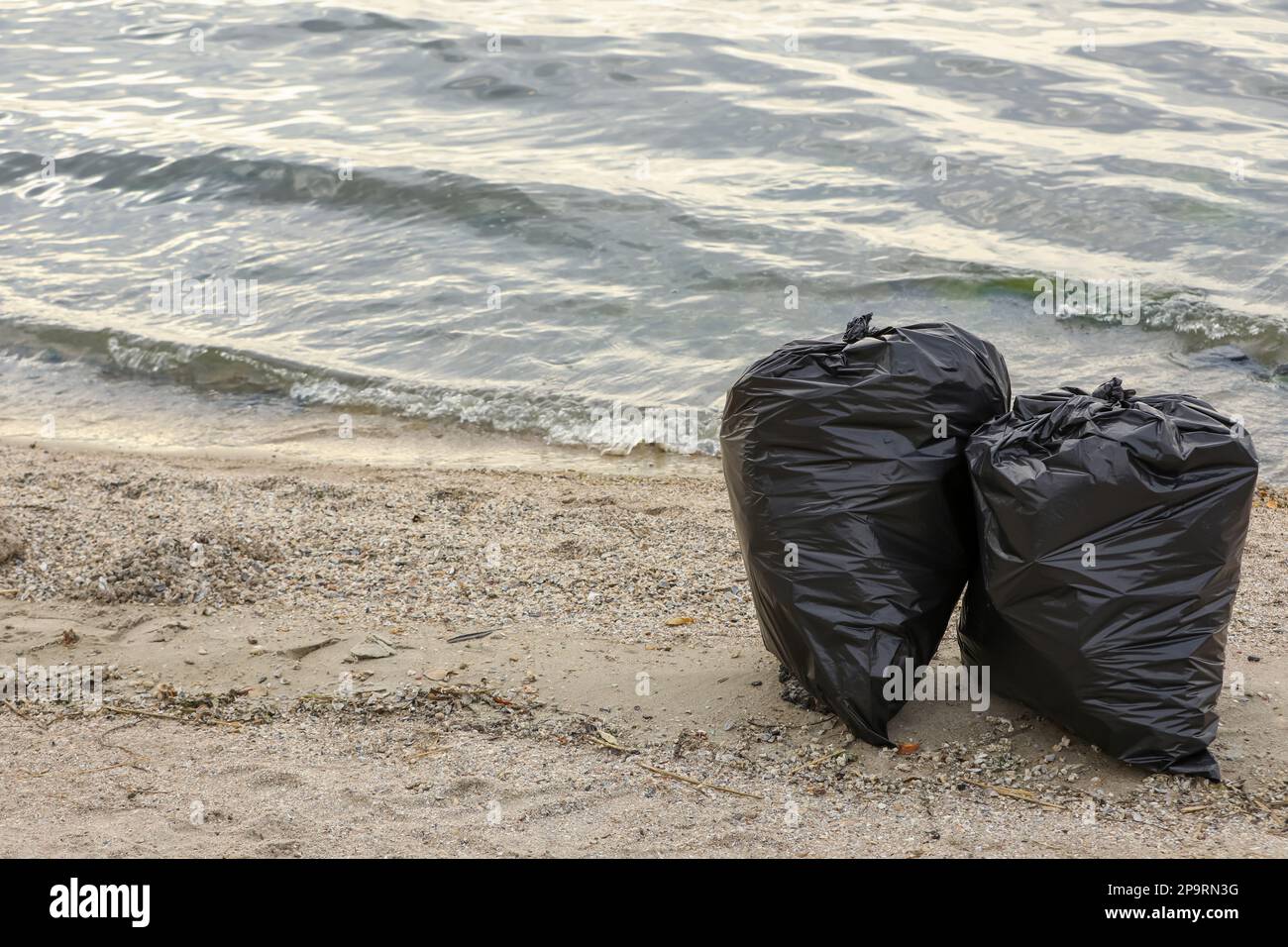 Sacs poubelles pleins de déchets sur la plage. Espace pour le texte Banque D'Images