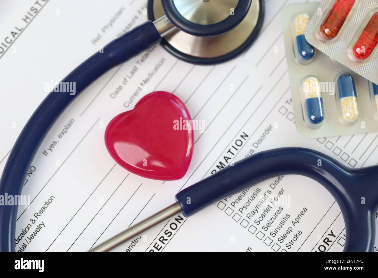 Cœur rouge, stéthoscope et pilules sur la feuille des antécédents médicaux du patient. Banque D'Images