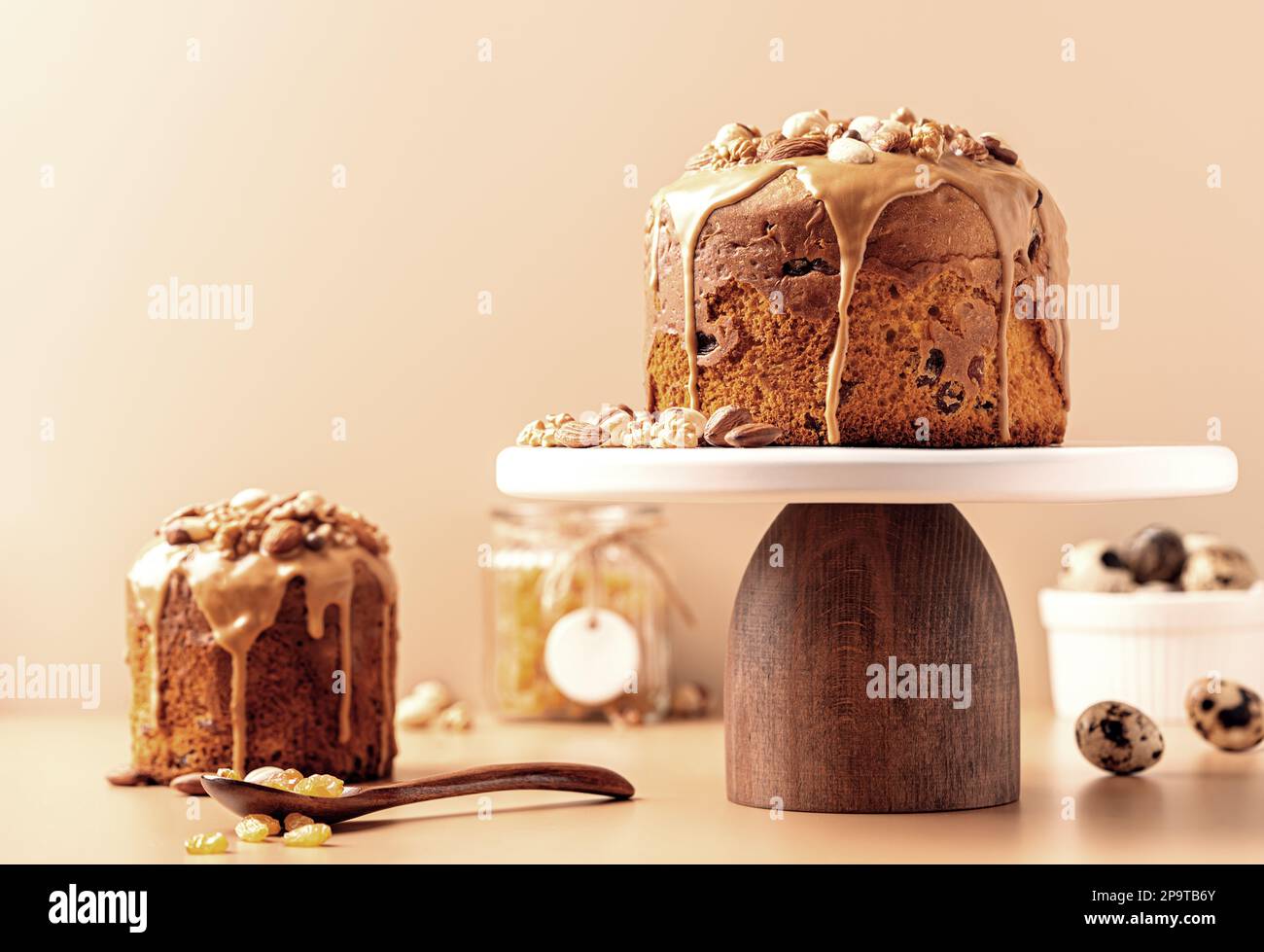 Gâteaux de Pâques émaillés de caramel décorés de noix sur fond pastel. Composition de Pâques avec gâteaux, noix, raisins secs et œufs de caille. Arrière-plan de Pâques avec espace de copie pour votre conception. Banque D'Images