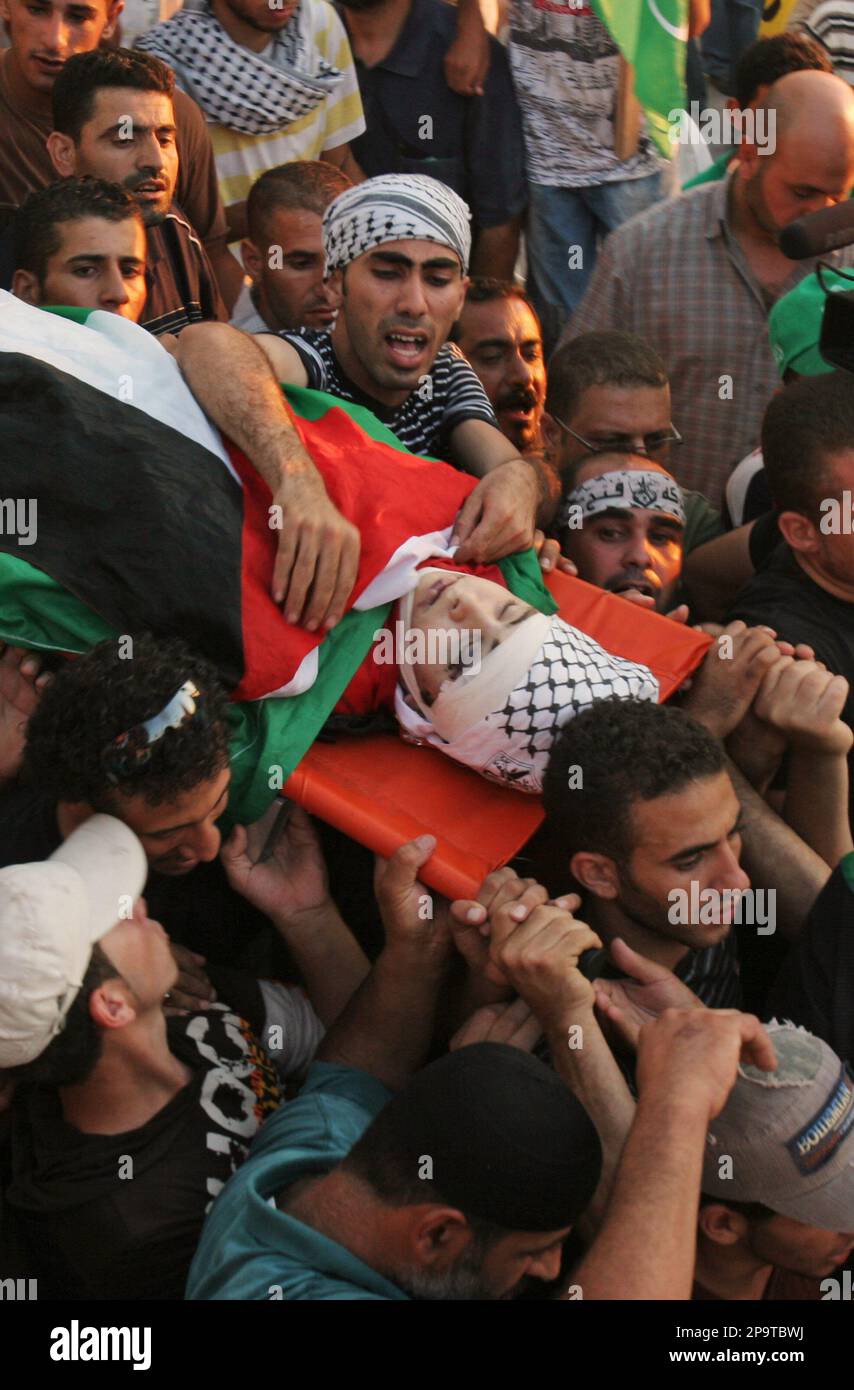 Palestinian mourners carry the body of Yussef Ameira during his funeral in the West Bank village of Nilin, near Ramallah, Monday Aug. 4, 2008. A Palestinian hospital official says a youth shot last week by Israeli soldiers at a protest in the West Bank has died of his wounds. An official at Ramallah Government Hospital says Yussef Ameira died Monday, five days after being shot in the head with two rubber-coated bullets. (AP Photo/Nasser Ishtayeh) Banque D'Images