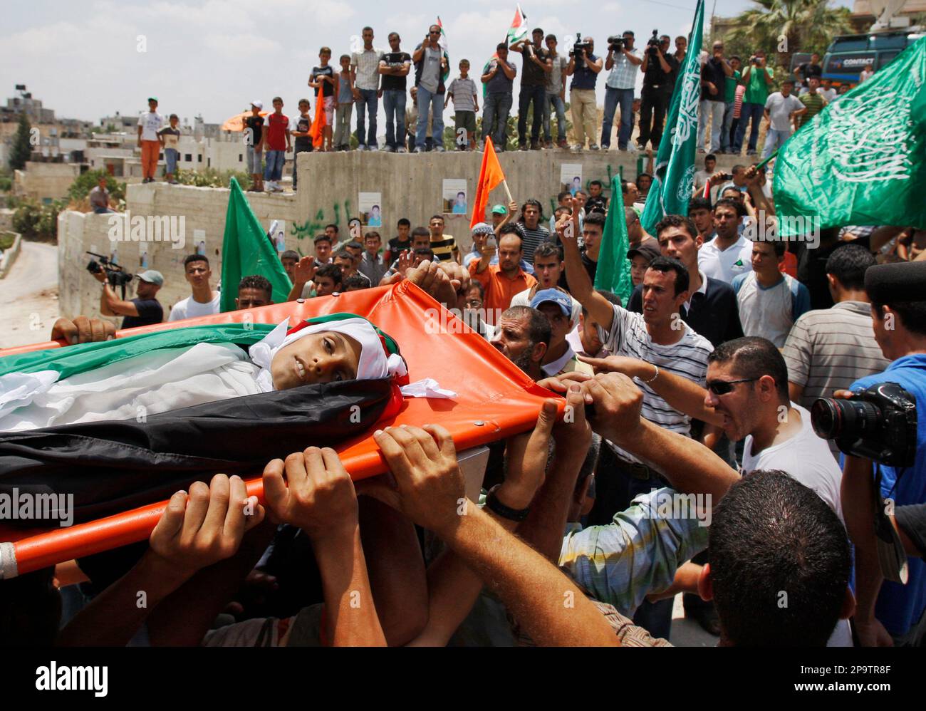 Palestinian mourners carry the body of Ahmed Moussa, 10 years, during his funeral in the West Bank village of Naalin, near Ramallah, Wednesday, July 30, 2008. An autopsy by Palestinian forensic doctors indicates that the 10-year-old West Bank boy killed in a confrontation with Israeli forces was shot by live fire, Palestinian officials said on Wednesday. Moussa was killed on Tuesday in the village of Naalin, during one of the frequent protests there against Israel's West Bank separation barrier. The Israeli military said it was investigating the boy's death. (AP Photo / Kevin Frayer) Banque D'Images