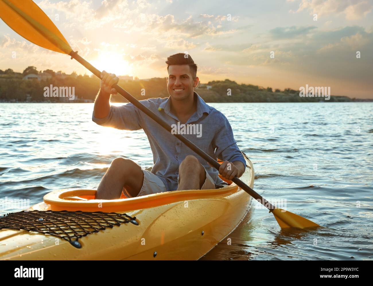 Un homme heureux faisant du kayak sur la rivière au coucher du soleil. En été Banque D'Images Un homme heureux faisant du kayak sur la rivière au coucher du soleil. En été Banque D'Images