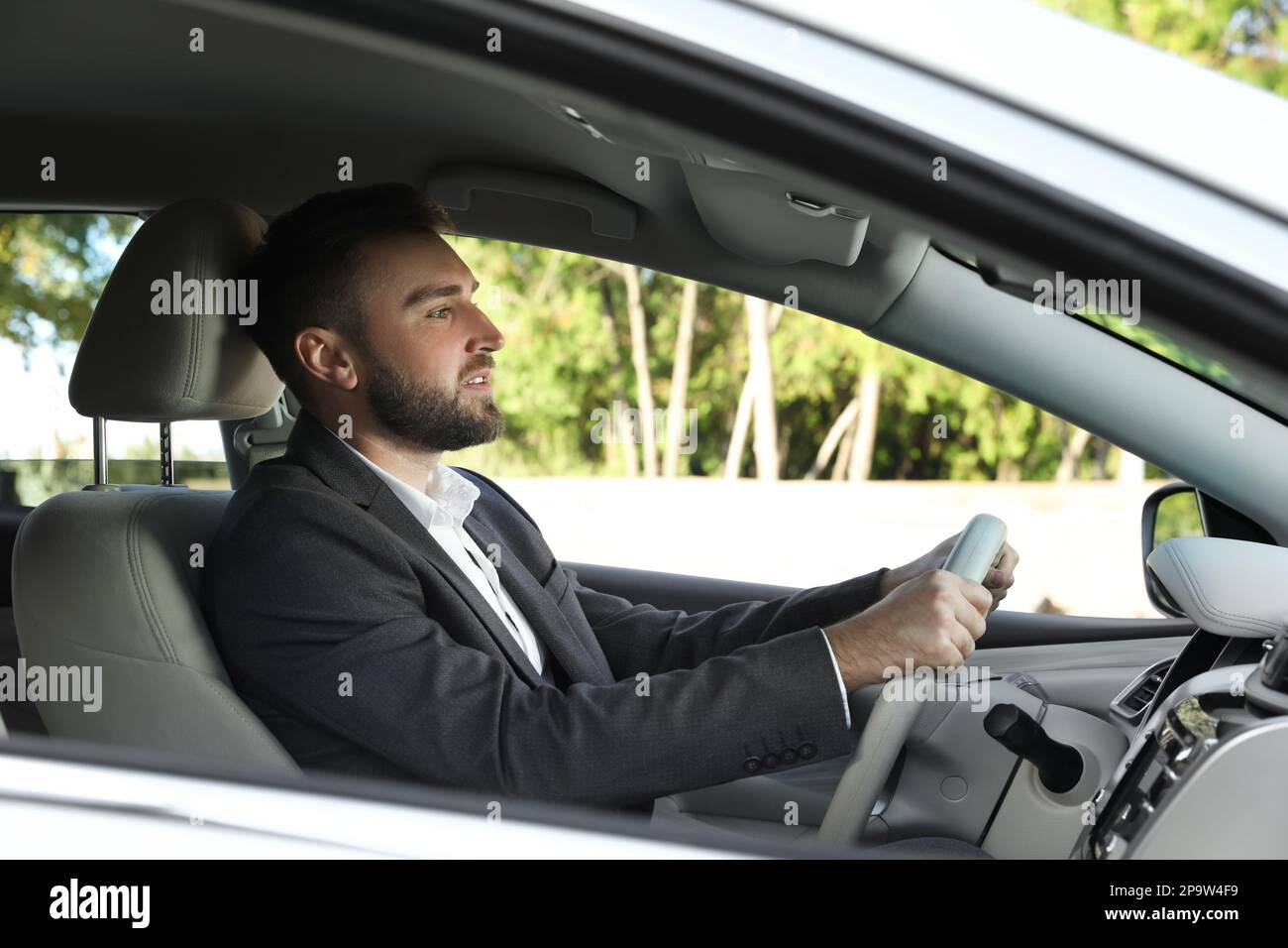 Beau jeune conducteur assis dans une voiture moderne Banque D'Images