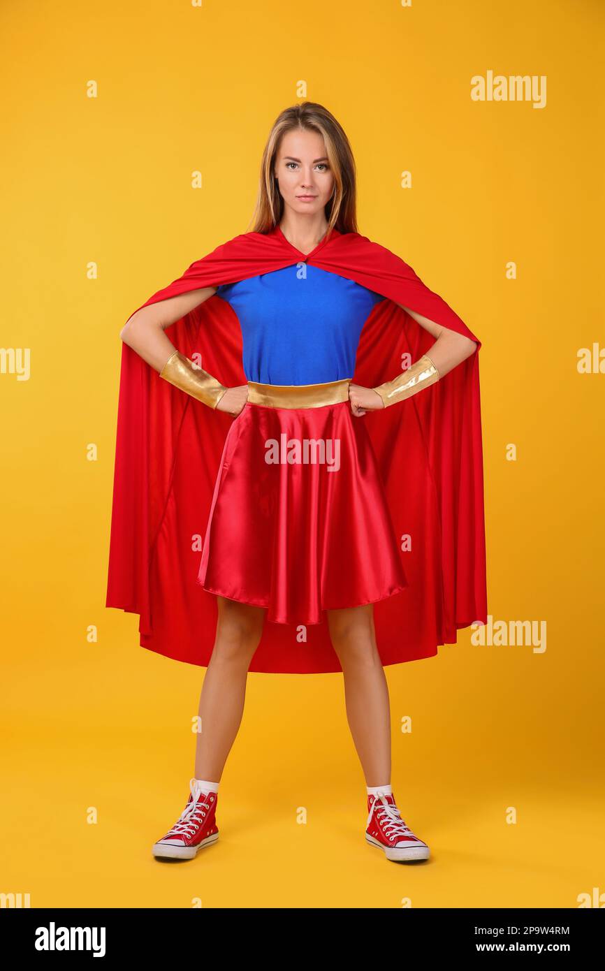 Femme confiante portant un costume de super-héros sur fond jaune Banque D'Images