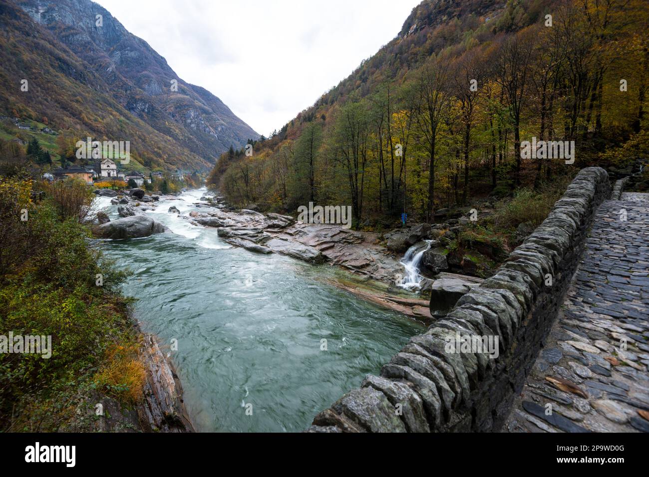 Pont romain sur la rivière qui coule rapidement dans le Val Verzasca, Suisse, jour d'automne nuageux, arbres colorés sur les pentes de la montagne et Lavertezzo Banque D'Images