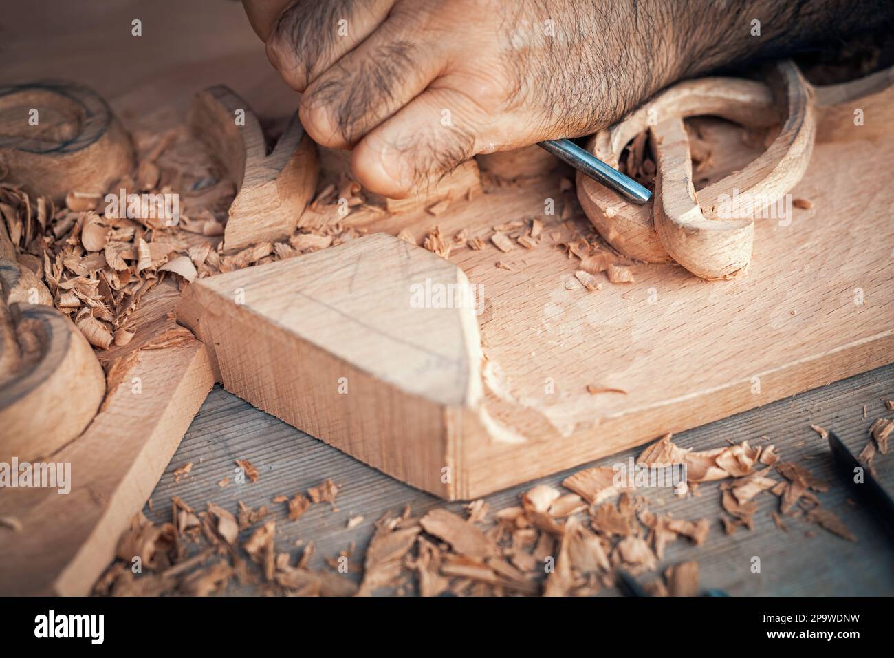 Un menuisier sculptant du bois sur une table. Bureau de menuiserie avec outils et couteaux. Menuisier à l'aide d'un burin. Banque D'Images