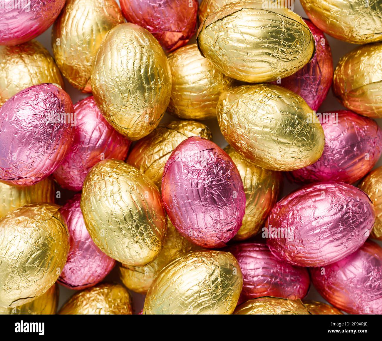 Gros plan de la pile d'œufs de Noël enveloppés de papier d'aluminium rose et doré. Concept joyeuses Pâques. Préparation pour les vacances. Vue de dessus, macro Banque D'Images