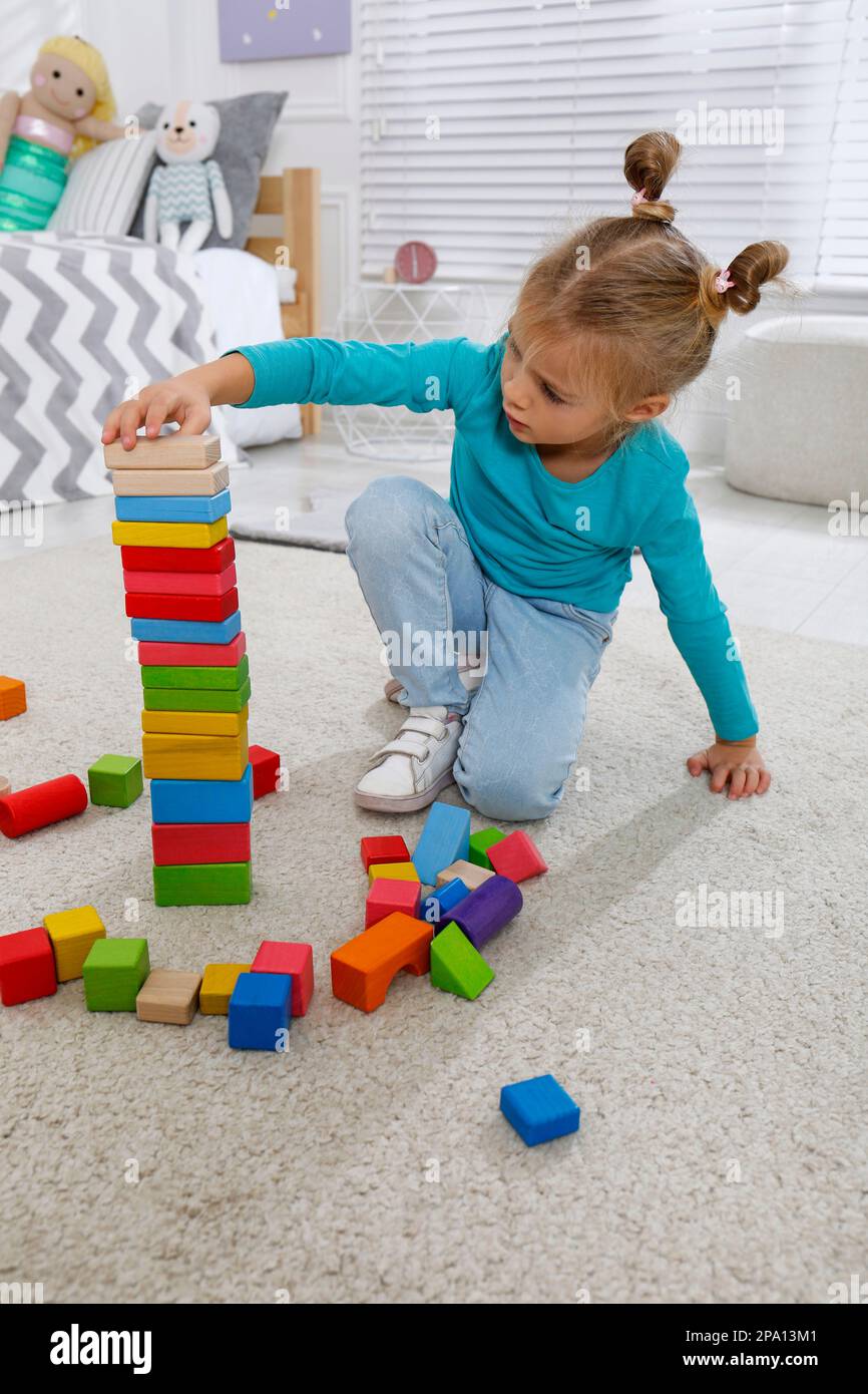 Petite fille mignonne jouant avec des blocs de construction colorés à la maison Banque D'Images
