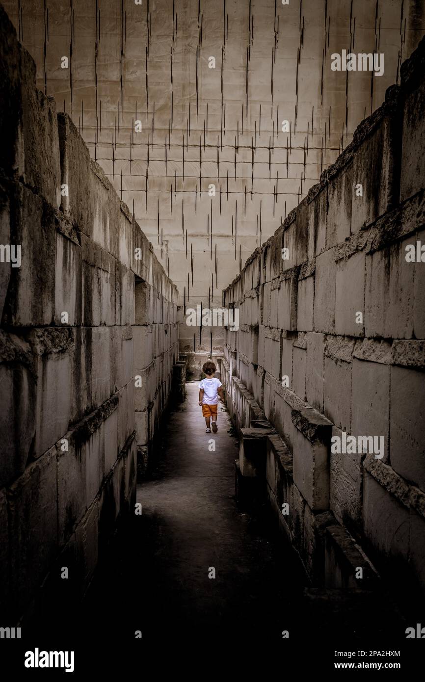 Un jeune enfant du Caucase marchant avec une perspective labyrinthe. Image conceptuelle de la situation dangereuse pendant l'enfance Banque D'Images