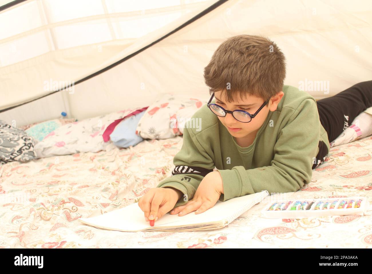 Un garçon survivant du tremblement de terre tirant dans une tente. Banque D'Images