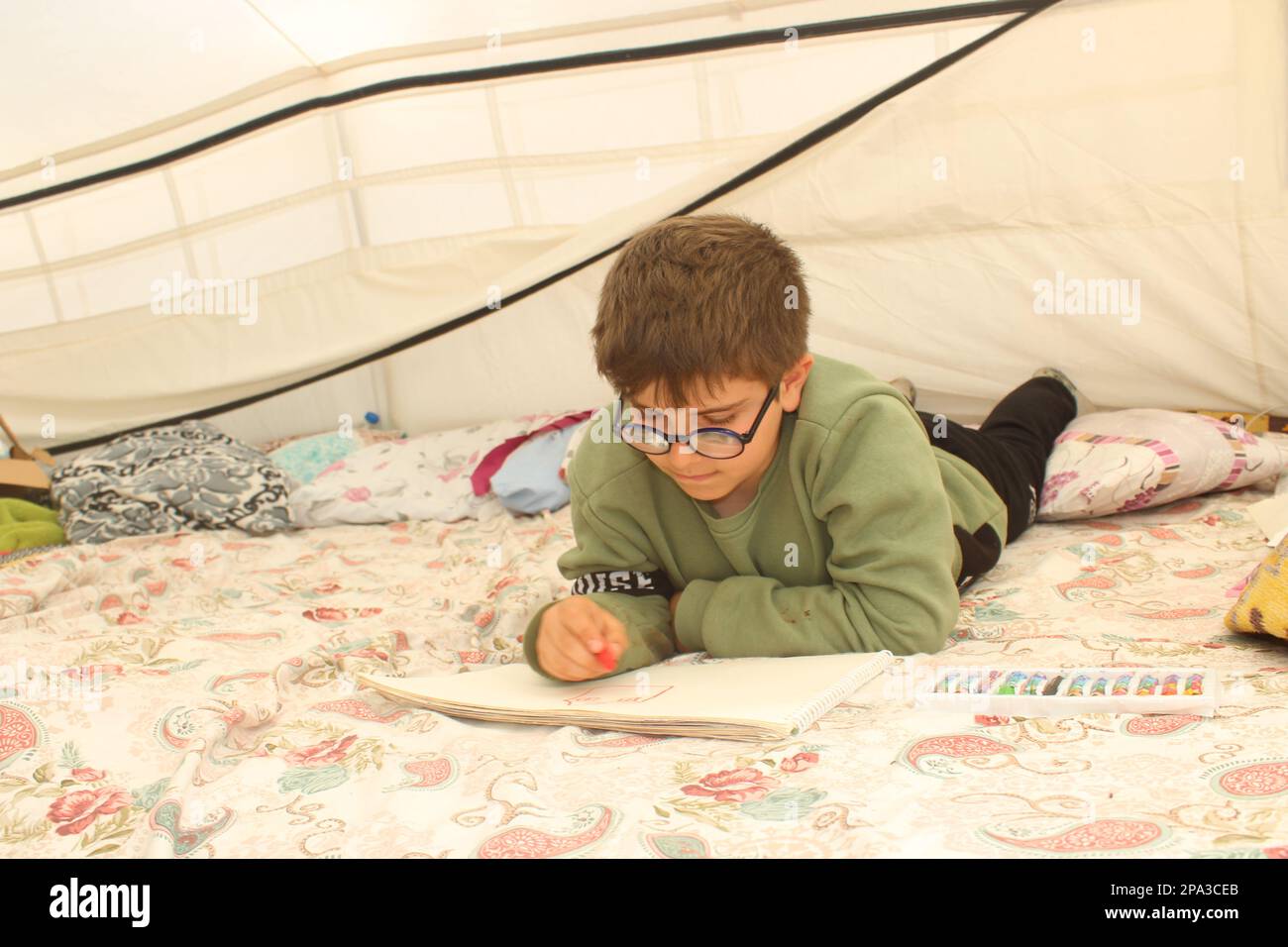 Un garçon survivant du tremblement de terre tirant dans une tente. Banque D'Images