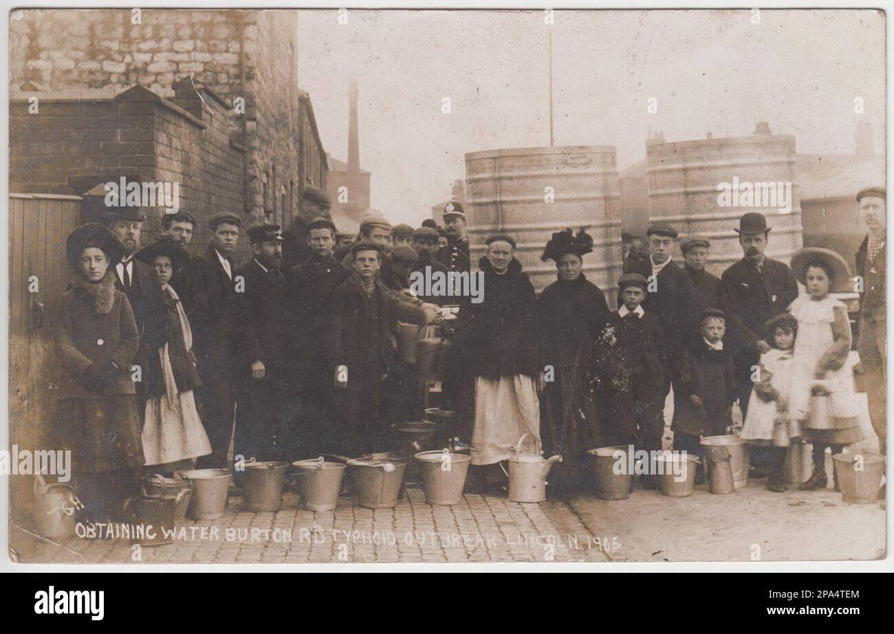 Épidémie de typhoïde de Lincoln, 1905 : groupe d'hommes, de femmes et d'enfants faisant la queue pour obtenir de l'eau propre dans Burton Road, Lincoln. Les gens ont un mélange de bateaux pour transporter l'eau, y compris des seaux en métaux, des arrosoirs et des cruches. Un policier fait le tour des grands conteneurs métalliques utilisés pour stocker l'eau. 131 personnes sont mortes à la suite de l'épidémie de typhoïde de 1904 à 1905 à Lincoln Banque D'Images