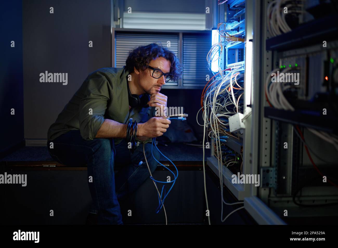 Un technicien réseau mâle connecte les câbles dans la salle des serveurs Banque D'Images
