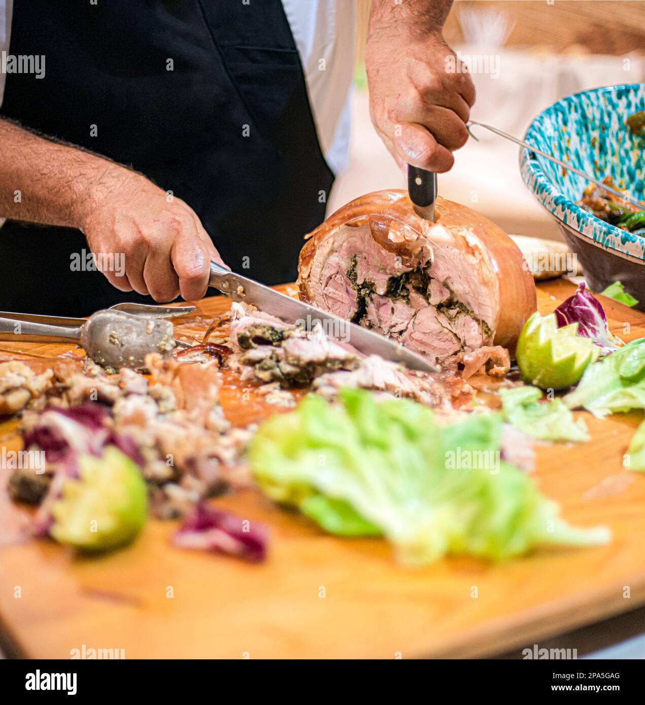 L'homme tranchant Porchetta, un plat italien, un rouleau de porc désossé, qui est rempli d'un mélange d'herbes, d'épices, et d'ail. Banque D'Images