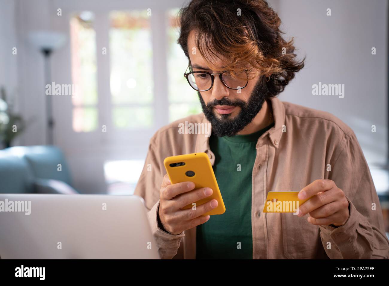 Homme magasiner en ligne en payant par carte de crédit et smartphone de la maison. Banque D'Images