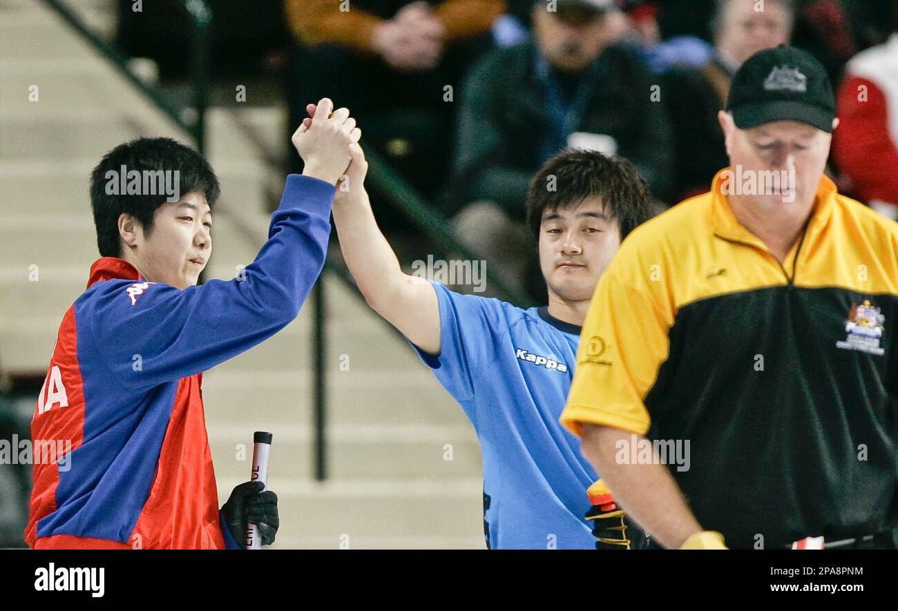 China's skip Fengchun Wang, left, high-fives teammate Xiaoming Xu with Australia's skip Hugh Millikin, right, during a match at the men's World Curling Championships, in Grand Forks, N.D., Thursday, April 10, 2008. China beat Australia 5-3. (AP Photo/Nati Harnik) Banque D'Images