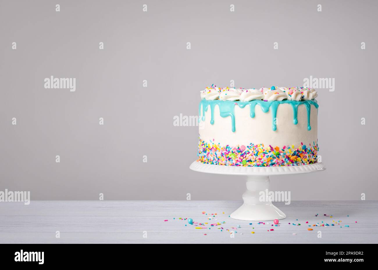 Gâteau d'anniversaire à la crème au beurre de vanille avec goutte de ganache bleu sarcelle et saupoudrer de couleur sur fond blanc. Tendance. copier l'espace. Banque D'Images