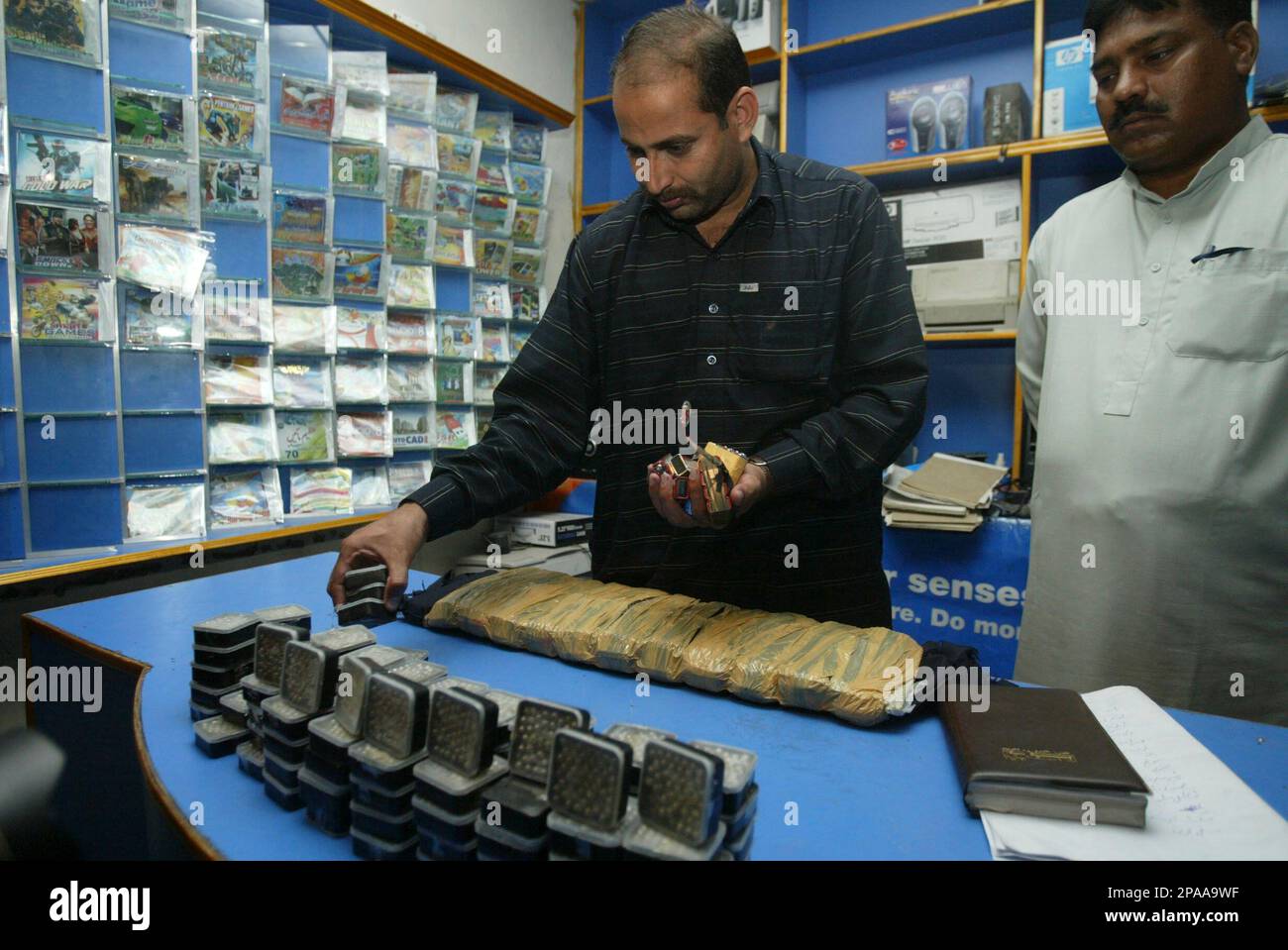 A Pakistani police officer in plain clothes arranges explosives and a suicide jacket, recovered from a militants' hideout in Lahore, Pakistan, Thursday, March 27, 2008. Police said they have arrested two militants suspects in connection with two recent suicide bombings in Lahore and seized sacks of explosives. (AP Photo/K.M.Chaudary) Banque D'Images