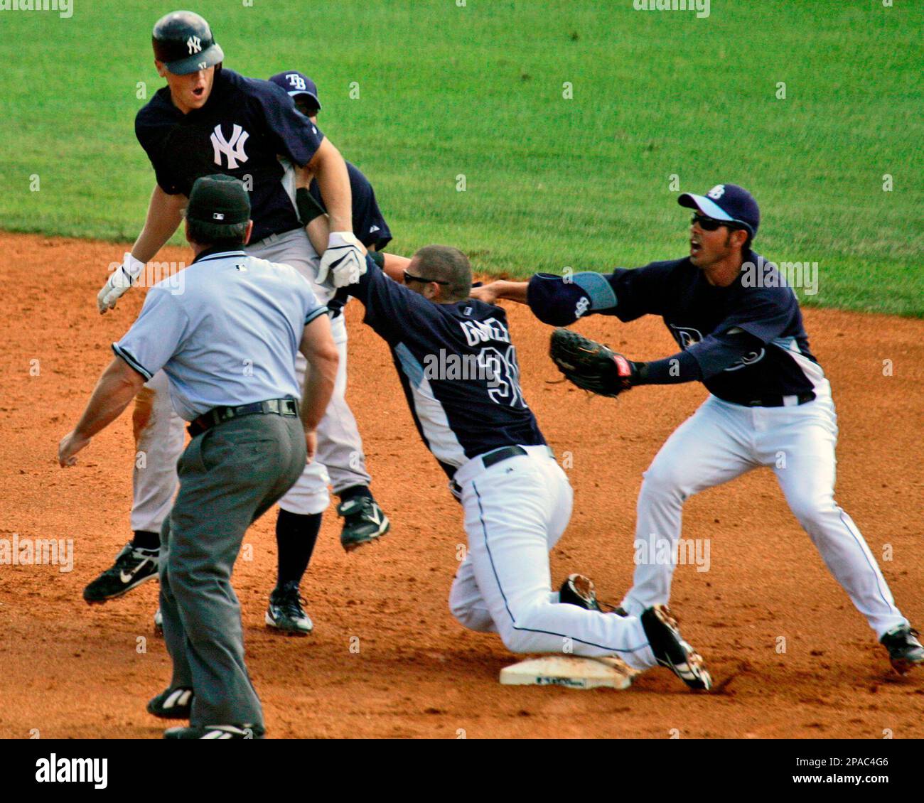Tampa Bay Rays right fielder Jonny Gomes, center, plows into New York Yankees' Shelley Duncan to begin a second inning bench clearing brawl during spring baseball action in St. Petersburg, Fla., Wednesday, March 12, 2008. At left is umpire Charlie Reliford, at right is Rays shortstop Josh Bartlett. (AP Photo/Gene J. Puskar) Banque D'Images