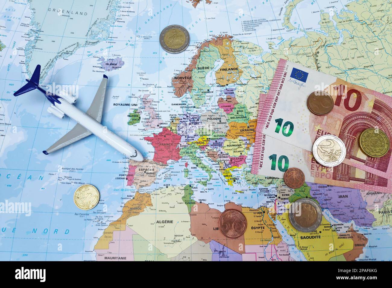 Paris, France - 19 février 2019: Composition d'une carte du monde centrée en Europe avec des billets et pièces en euros ainsi qu'un avion de jouet. Banque D'Images