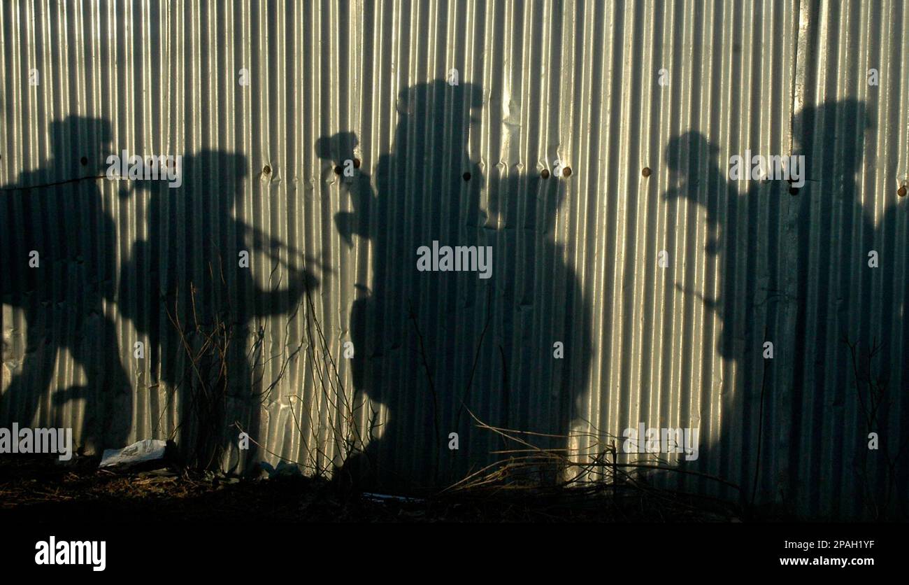 The shadows of Indian Paramilitary soldiers are seen on the tin wall of a house as they arrive near the site of a gun battle in Drusoo village, 65 kilometers, 40 miles, from Srinagar, India, Friday, Feb. 1, 2008. Five suspected Islamic rebels were killed in different gun battles with government forces in India controlled Kashmir, according to police. (AP Photo/ Dar Yasin) Banque D'Images