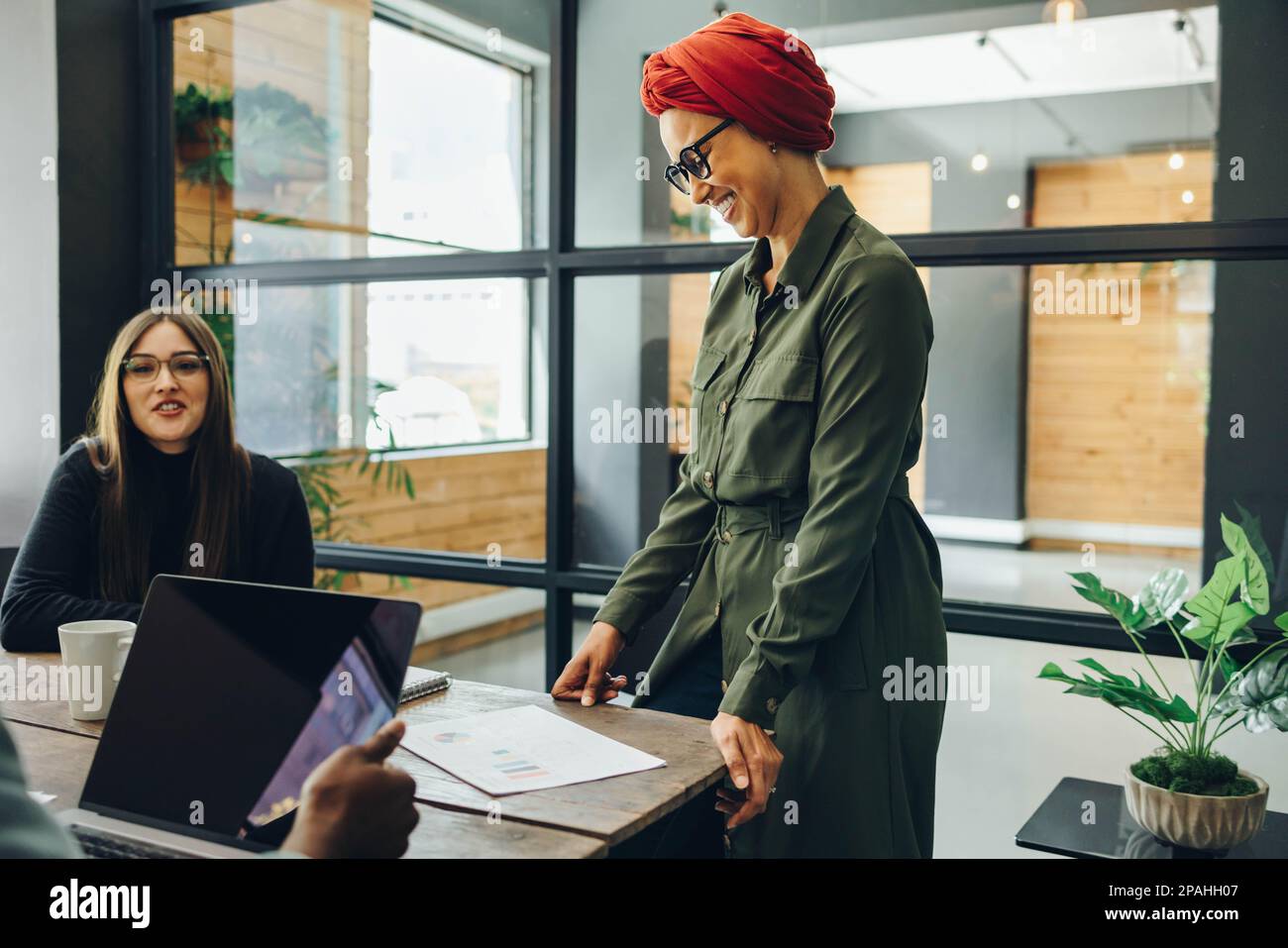 Femme d'affaires musulmane joyeuse ayant une réunion avec ses collègues dans une salle de réunion moderne. Un professionnel heureux portant un foulard dans un multitu Banque D'Images