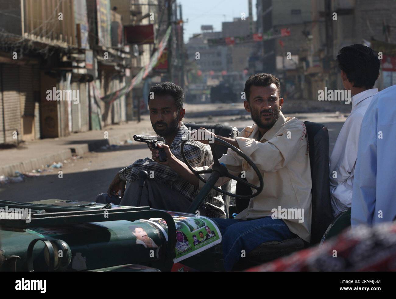 Armed Pakistani supporters of slain opposition leader Benazir Bhutto drive through the streets and past closed shops in Karachi, Pakistan after days of rioting Sunday Dec. 30, 2007. After days of violent reaction to the killing of Bhutto, Karachi remains a city under lock down. (AP Photo/David Guttenfelder) Banque D'Images