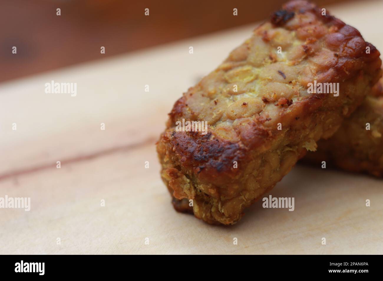 un gros plan de la tempeh frite sur une planche à découper en bois. Concept de la cuisine traditionnelle indonésienne. Banque D'Images