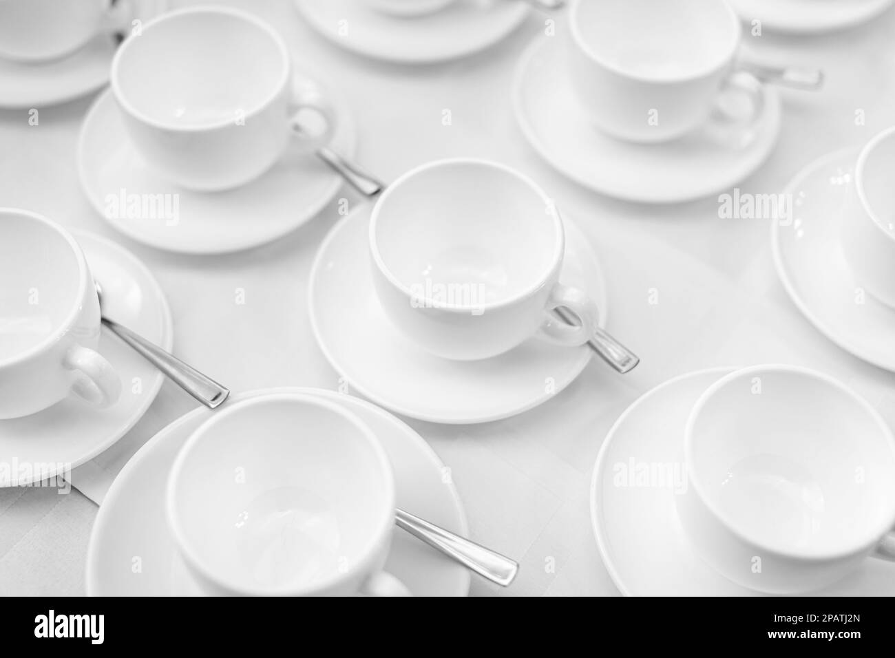 De nombreuses rangées de tasses à café ou à thé en céramique blanche. Lignes de tasses à café devant la salle de conférence. Soucoupes et soucoupes en céramique blanche disposées sur un buffet Banque D'Images