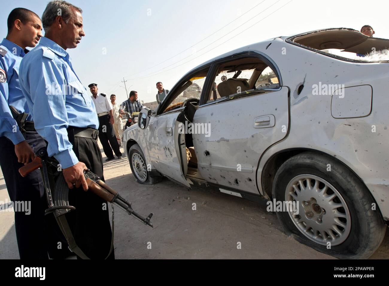 Two Iraqi policemen inspect the damage to a car after a failed assassination attempt on a senior politician in Basra, Iraq's second-largest city, 550 kilometers (340 miles) southeast of Baghdad, Thursday, Nov. 8, 2007. Qahtan al-Mousawi, general director of the Basra education department, was traveling in a two-car convoy through central Basra when a roadside bomb went off next to the convoy, injuring four persons, police said. (AP Photo/Nabil al-Jurani) Banque D'Images