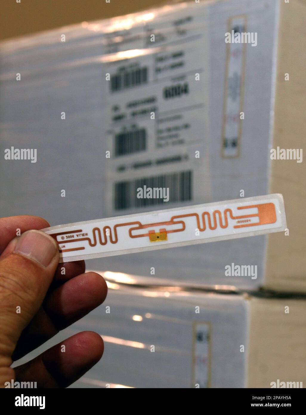 The Alien Squiggle Tag, an RFID tag that uses a small chip for tracking, is shown in front of a stack of traditional cases on a shipping pallet on Monday, Oct. 22, 2007 at the RFID Solutions Center in Miamisburg, Ohio. Radio frequency identification technology, or RFID, consists of tiny computer chips and antennas that are placed on or in items and emit radio waves that transmit information to electronic reading devices. The technology can be used for such things as tracking inventory, identifying livestock and pharmaceuticals, and preventing the theft of books and merchandise from libraries a Banque D'Images
