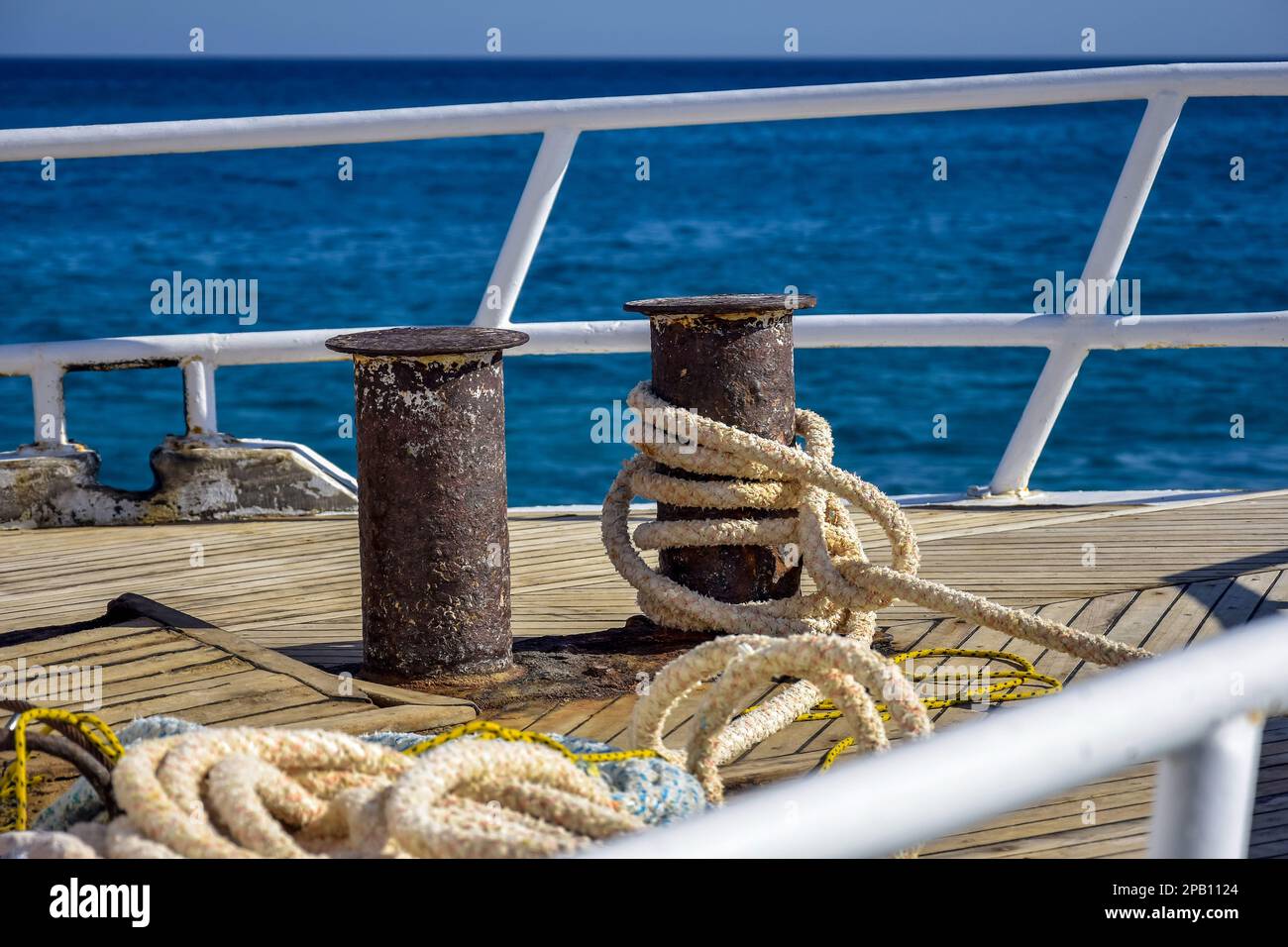 Arc de yacht blanc sur fond de bleu de mer.épaisse corde d'ancrage est enroulé autour des bollards. Rambardes-clôtures en acier. Vue de dessus. Gros plan. Banque D'Images