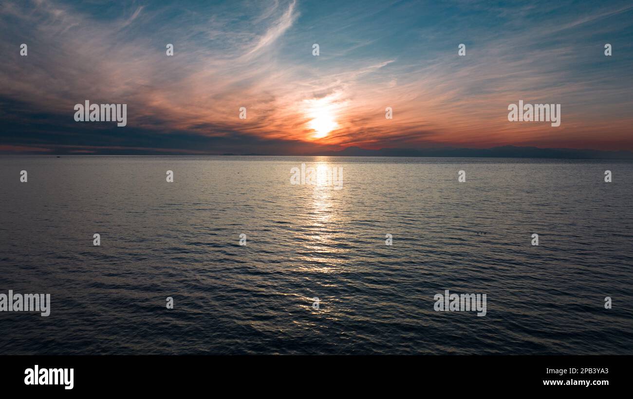 Coucher de soleil sur la mer. Le soleil rouge se coucher parmi les nuages. ciel bleu Banque D'Images
