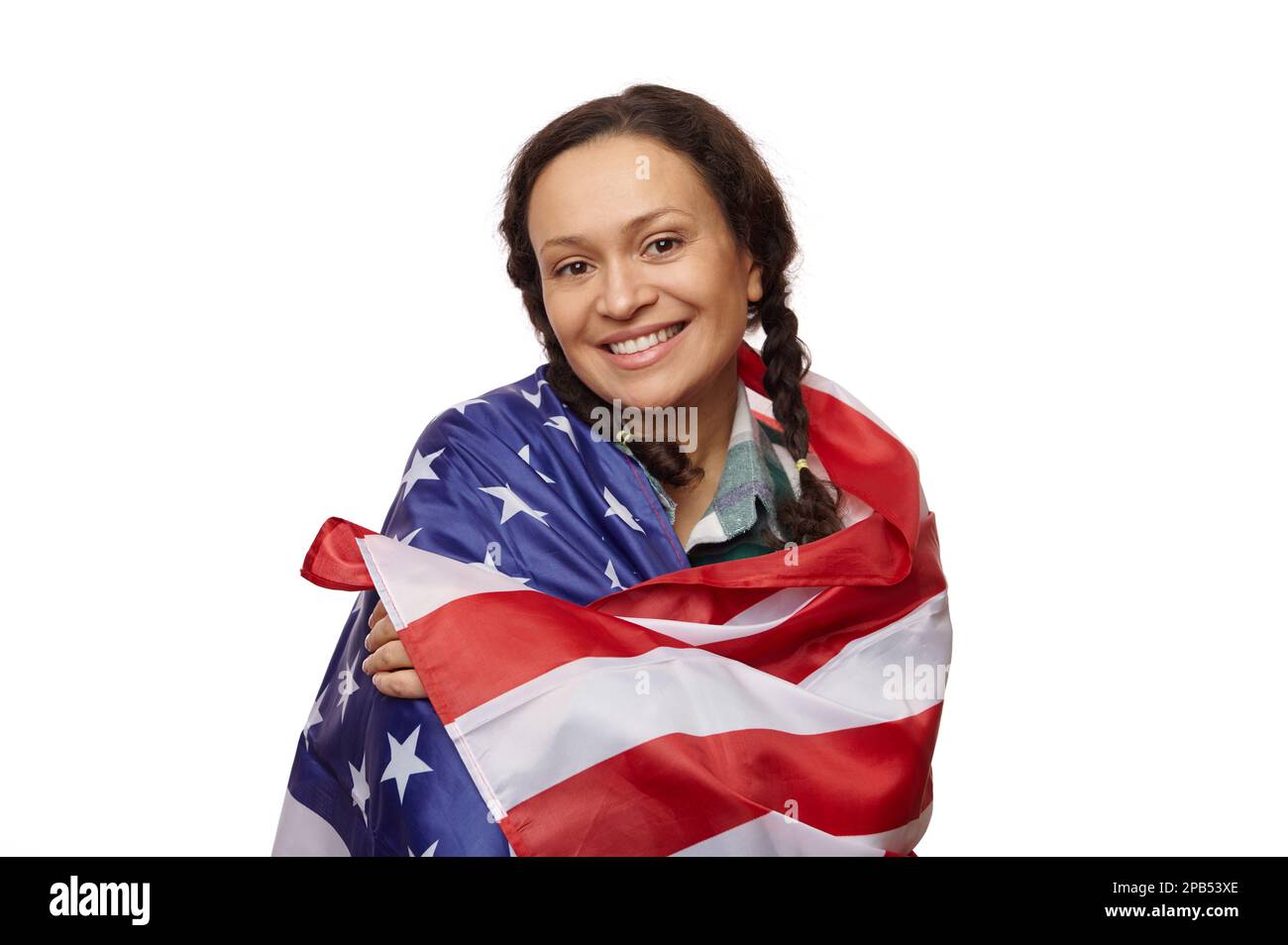 Portrait isolé sur fond blanc d'une charmante femme d'âge moyen ethnique, souriant à l'appareil photo, enveloppée d'un drapeau américain Banque D'Images